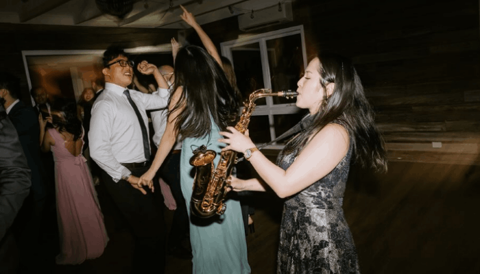 Female saxophonist performing at energetic Melbourne wedding reception.